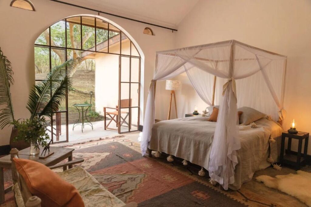 Four-poster bed with mosquito net, carpet and a big glass door to the terrace