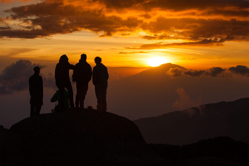 Wanderer stehen bei Sonnenaufgang auf dem Gipfel des Kilimandscharo