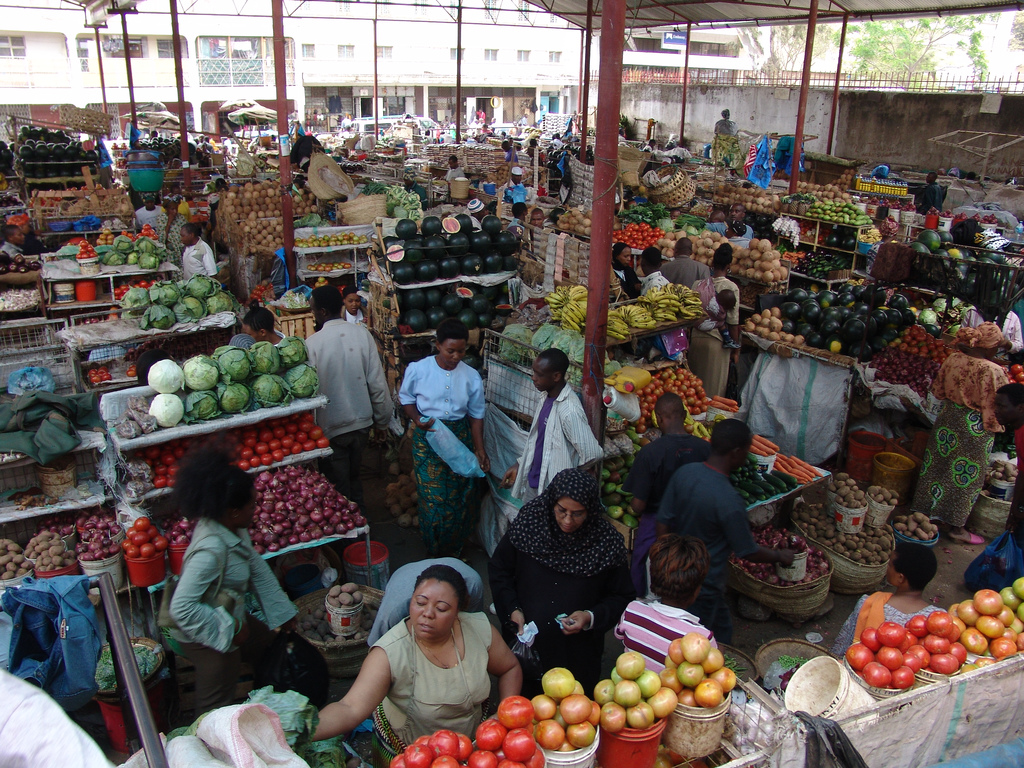 Many people in a market in Arusha with fruit and vegetables