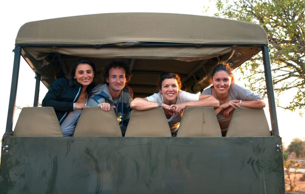 Three women and one man looking out the back of a safari jeep