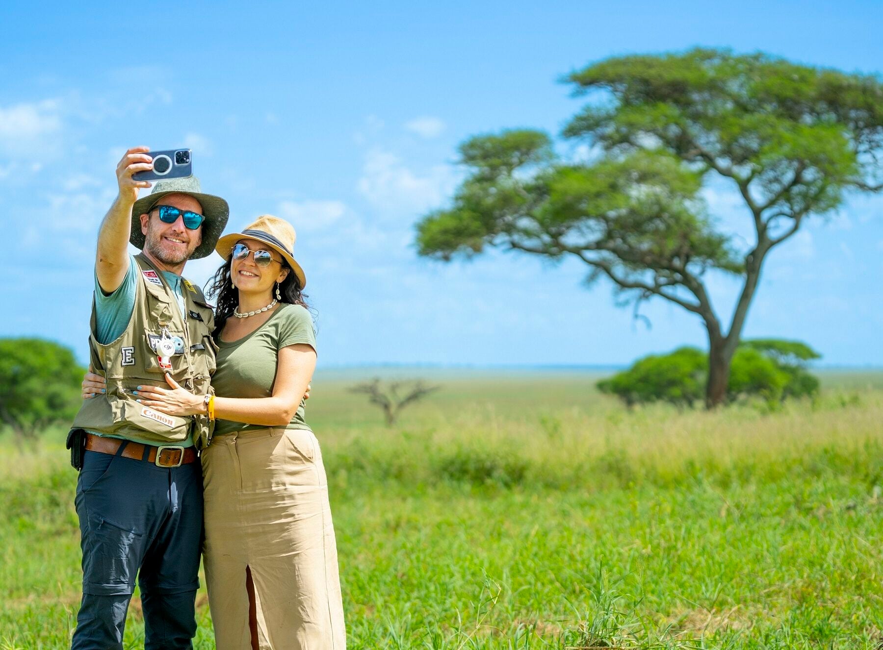 A couple in Tanzania taking a selfie in front of an acacia tree