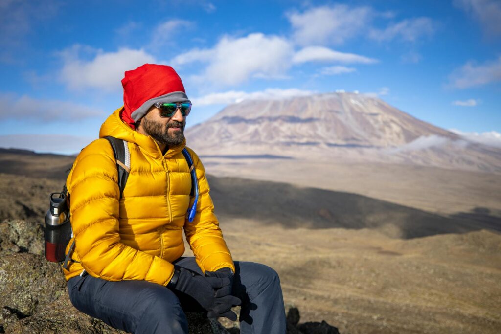 Hombre sentado en una roca mientras escala el Kilimanjaro