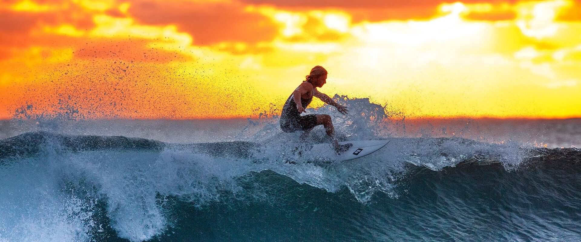 Woman surfing on a wave during sunset