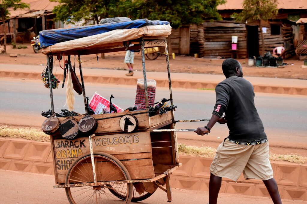 Man pushing a cart with African sculptures