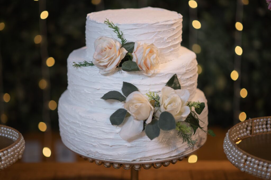 Weiße, dreistöckige Hochzeitstorte mit Blumen